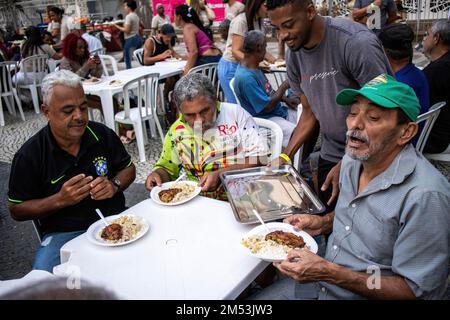 Rio de Janeiro, Brasile. 24th Dec, 2022. I volontari servono la cena di beneficenza per i senzatetto la sera di Natale. Cena di Natale per i senzatetto nel centro di Rio de Janeiro. 150 volontari sotto la chiesa Battista mobilitati in piazza Largo de Carioca per servire la cena di Natale per le persone che vivono per le strade del centro di Rio de Janeiro. Per 15 anni la chiesa Battista ha organizzato questo evento per i senzatetto. Nella seconda città più grande del Brasile, circa 15.000 persone vivono per strada senza casa. Credit: SOPA Images Limited/Alamy Live News Foto Stock