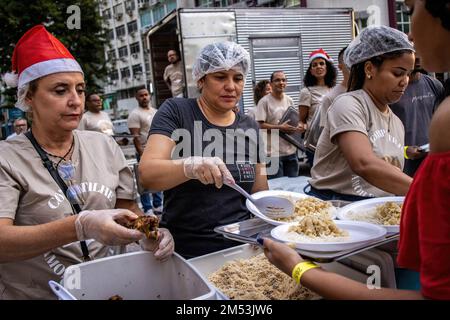 Rio de Janeiro, Brasile. 24th Dec, 2022. I volontari servono la cena di beneficenza per i senzatetto la sera di Natale. Cena di Natale per i senzatetto nel centro di Rio de Janeiro. 150 volontari sotto la chiesa Battista mobilitati in piazza Largo de Carioca per servire la cena di Natale per le persone che vivono per le strade del centro di Rio de Janeiro. Per 15 anni la chiesa Battista ha organizzato questo evento per i senzatetto. Nella seconda città più grande del Brasile, circa 15.000 persone vivono per strada senza casa. Credit: SOPA Images Limited/Alamy Live News Foto Stock