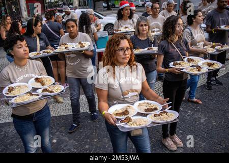 Rio de Janeiro, Brasile. 24th Dec, 2022. I volontari iniziano a servire la cena di beneficenza per i senzatetto la sera di Natale. Cena di Natale per i senzatetto nel centro di Rio de Janeiro. 150 volontari sotto la chiesa Battista mobilitati in piazza Largo de Carioca per servire la cena di Natale per le persone che vivono per le strade del centro di Rio de Janeiro. Per 15 anni la chiesa Battista ha organizzato questo evento per i senzatetto. Nella seconda città più grande del Brasile, circa 15.000 persone vivono per strada senza casa. Credit: SOPA Images Limited/Alamy Live News Foto Stock