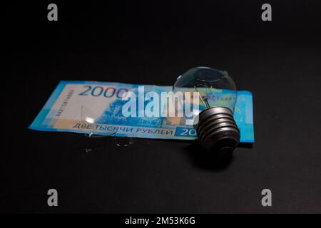 Lampadina rotta con pezzi di vetro su rublo russo. Concetto di prezzi dell'elettricità e crisi dell'elettricità in Russia Foto Stock