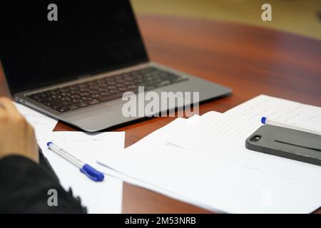 Una persona professionista in una riunione sta scrivendo o prendendo appunti su carta con il portatile aperto. una persona sta studiando duro. Foto Stock