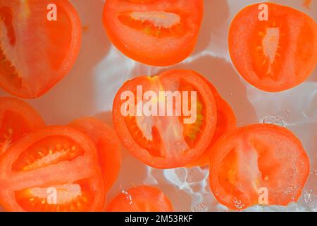 Primo piano fette fresche di pomodoro succoso su sfondo bianco. Fette di pomodoro in acqua frizzante su fondo bianco, primo piano Foto Stock