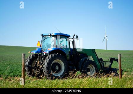 Trattore agricolo con turbina eolica che fornisce energia eolica - energia sostenibile in azienda agricola in campagna. Foto Stock