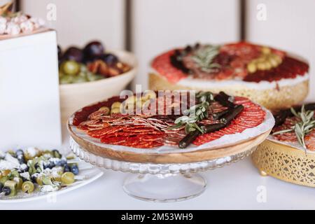 Antipasti di carne e formaggio. Vari tipi di salumi, salsicce, snacks al parmigiano, olive verdi, rosmarino, tapas su piatti di legno. N. serie Foto Stock