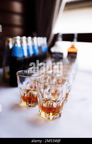molti bicchieri con cognac, brandy o whisky stand al bar. Varie bevande alcoliche in bicchieri durante la festa. Foto Stock