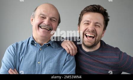 Felice padre anziano maturo e figlio cresciuto in piedi insieme, abbracciando, guardando la macchina fotografica Foto Stock