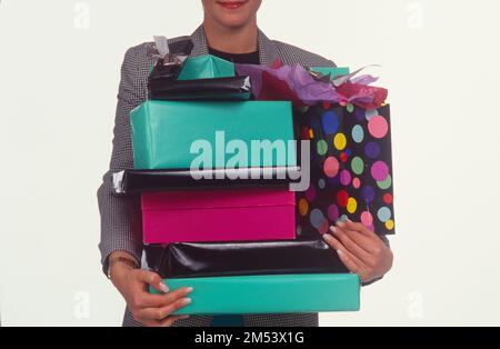 Primo piano di una donna, ben vestita tenendo pacchetti regalo avvolti tra le braccia Foto Stock