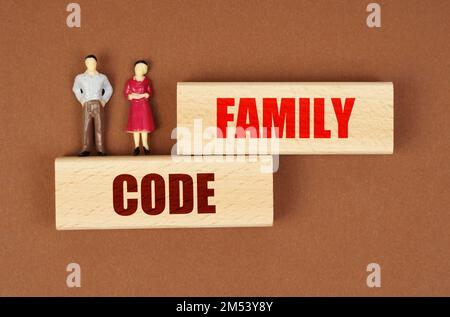 Concetto di business e persone. Su blocchi di legno con l'iscrizione - Codice Famiglia, ci sono figure in miniatura di persone. Foto Stock