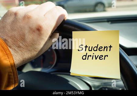 Concetto di trasporto. Un uomo tiene il volante, accanto a un adesivo con la scritta - conducente studente Foto Stock