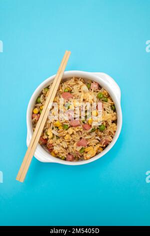Riso con mais. piselli, prosciutto su ciotola bianca piccola Foto Stock