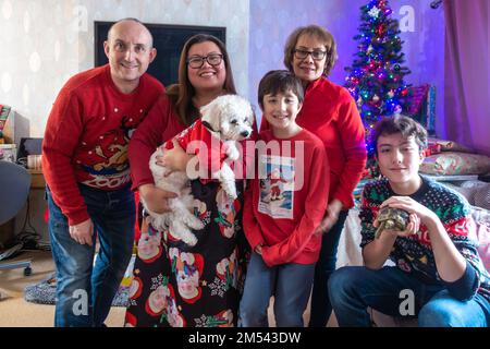 Una posa di famiglia per un ritratto con il loro piccolo, cane cavapoo bianco su e animale domestico tartaruga giorno di Natale Foto Stock