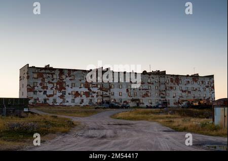 Un edificio abbandonato a più piani sorge nel mezzo del campo. Foto Stock