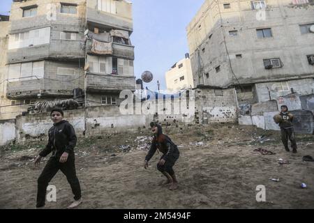 Gaza, Palestina. 25th Dec, 2022. I bambini rifugiati palestinesi giocano a calcio nel campo di Jabalia nella striscia di Gaza settentrionale. A causa degli elevati tassi di disoccupazione e della mancanza di opportunità di lavoro a Gaza, un numero crescente di famiglie si trova ad affrontare la povertà dopo aver perso il lavoro negli ultimi dieci anni del blocco di Gaza e delle guerre israeliane contro la striscia di Gaza. Credit: SOPA Images Limited/Alamy Live News Foto Stock