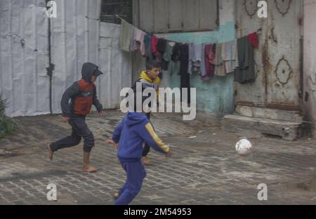 Gaza, Palestina. 25th Dec, 2022. I bambini rifugiati palestinesi giocano a calcio nel campo di Jabalia nella striscia di Gaza settentrionale. A causa degli elevati tassi di disoccupazione e della mancanza di opportunità di lavoro a Gaza, un numero crescente di famiglie si trova ad affrontare la povertà dopo aver perso il lavoro negli ultimi dieci anni del blocco di Gaza e delle guerre israeliane contro la striscia di Gaza. Credit: SOPA Images Limited/Alamy Live News Foto Stock