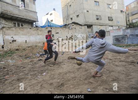 Gaza, Palestina. 25th Dec, 2022. I bambini rifugiati palestinesi giocano a calcio nel campo di Jabalia nella striscia di Gaza settentrionale. A causa degli elevati tassi di disoccupazione e della mancanza di opportunità di lavoro a Gaza, un numero crescente di famiglie si trova ad affrontare la povertà dopo aver perso il lavoro negli ultimi dieci anni del blocco di Gaza e delle guerre israeliane contro la striscia di Gaza. Credit: SOPA Images Limited/Alamy Live News Foto Stock