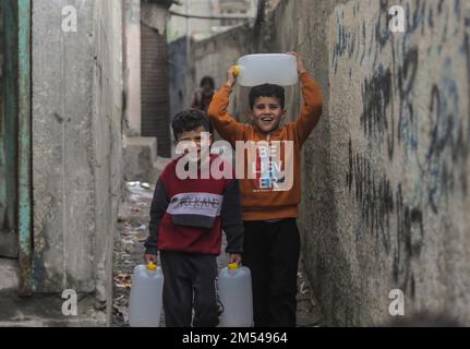 Gaza, Palestina. 25th Dec, 2022. I bambini rifugiati palestinesi trasportano acqua potabile nelle loro case nel campo di Jabalia, nella striscia di Gaza settentrionale. A causa degli elevati tassi di disoccupazione e della mancanza di opportunità di lavoro a Gaza, un numero crescente di famiglie si trova ad affrontare la povertà dopo aver perso il lavoro negli ultimi dieci anni del blocco di Gaza e delle guerre israeliane contro la striscia di Gaza. (Foto di Mahmoud Issa/SOPA Images/Sipa USA) Credit: Sipa USA/Alamy Live News Foto Stock