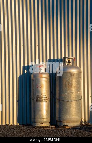 Bombole di GPL o di gas di petrolio liquido che si trovano all'esterno di un edificio in metallo nel tardo pomeriggio alla luce del sole nel nuovo Galles del Sud, Australia Foto Stock