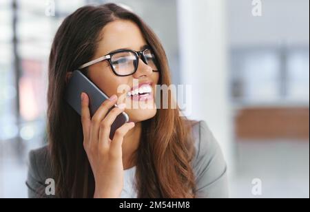 Shes sempre disponibile per parlare di affari. una giovane donna d'affari che parla su un cellulare in un ufficio. Foto Stock
