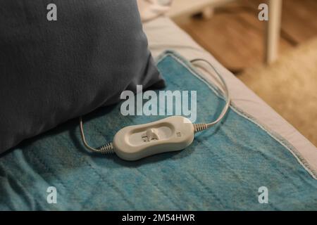 Riscaldamento elettrico con controller sul letto di notte, primo piano Foto Stock