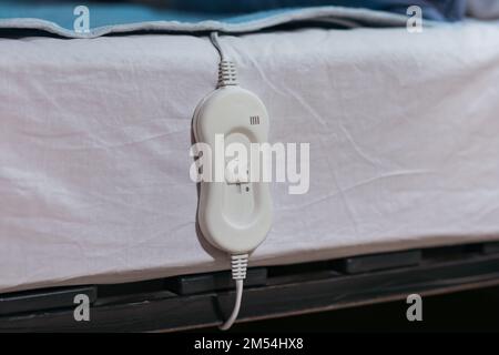 Riscaldamento elettrico con controller sul letto di notte, primo piano Foto Stock