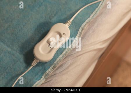 Riscaldamento elettrico con controller sul letto di notte, primo piano Foto Stock