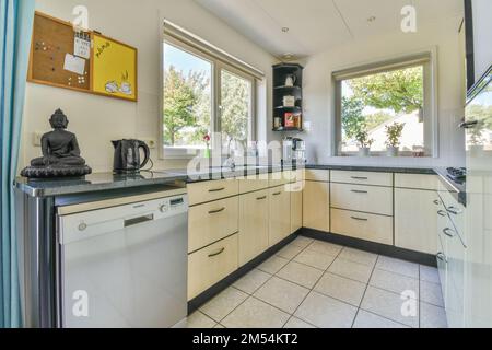 una zona cucina con armadietti bianchi e ripiani neri sui banconi in questa foto è presa dall'interno Foto Stock