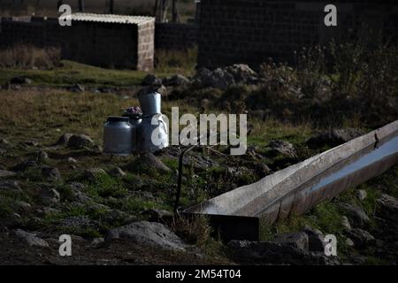 L'acqua che si versa da un tubo in un tubo metallico in un villaggio Foto Stock