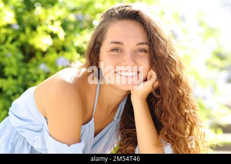 Felice donna di bellezza sorridente alla macchina fotografica con denti perfetti seduti in un parco Foto Stock