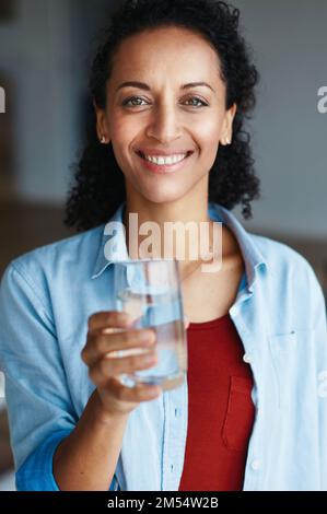 Ricordisi di bere i vostri otto vetri giornalmente. Ritratto di una donna che beve un bicchiere d'acqua a casa. Foto Stock