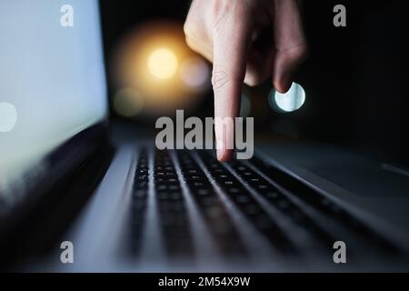 Un tasto alla volta. un pirata informatico irriconoscibile che utilizza un computer portatile a tarda notte. Foto Stock