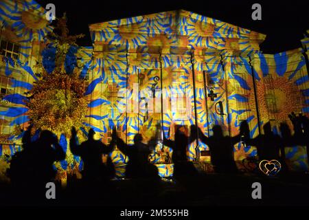 Non esclusiva: KIEV, UCRAINA - 23 DICEMBRE 2022 - la gente tiene le mani accanto alla costruzione del Museo Nazionale di Storia dell'Ucraina illuminato come Foto Stock