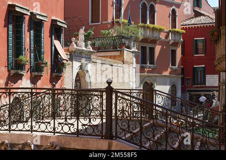 Architettura veneziana con ringhiera in ferro battuto in primo piano e gondoliere e turisti sullo sfondo, Venezia, Italia Foto Stock