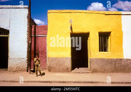 Etiopia, 1970s, Harar, un ragazzo in piedi per strada, casa gialla, regione di Harari, Africa orientale, Foto Stock