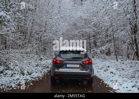 Un'auto nel mezzo di una foresta innevata che vi porta in un viaggio verso una favola invernale Foto Stock