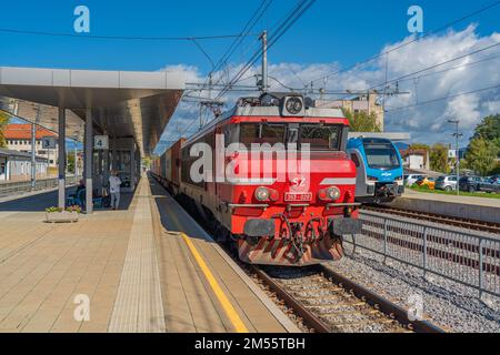 Celje, Slovenia - Oktober 03, 2022: Ferrovie slovene, treni pubblici di trasporto elettrici rossi e blu in piedi in una stazione ferroviaria. Foto Stock