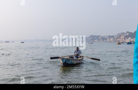 I turisti si godono un giro in barca nel fiume gange insieme al branco di gabbiani di mare a varanasi durante la mattina presto. Barcaiolo che naviga sulla barca di legno. Foto Stock