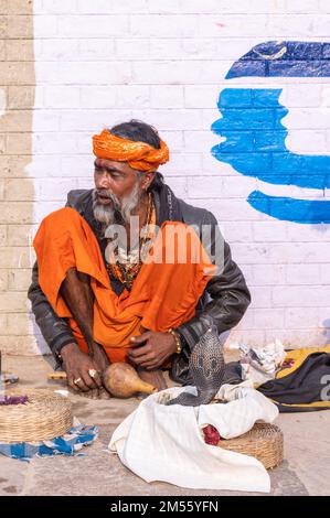 Ritratto di un vecchio incantatore di serpenti maschio che esegue il lato del fiume con il serpente nella città di varanasi per la sua sopravvivenza e attira turisti. Foto Stock