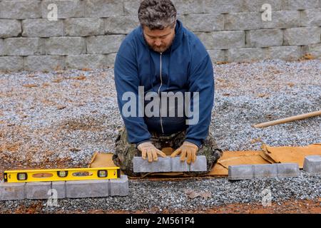 Durante il progetto di costruzione del marciapiede, l'operatore sta posando l'asfaltatrice in calcestruzzo. Foto Stock