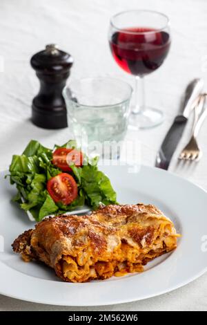 porzione di lasagna su un piatto bianco Foto Stock