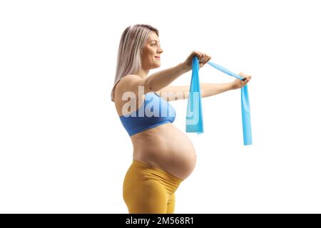 Foto di profilo di una donna incinta che si esercita con una fascia stretching isolata su sfondo bianco Foto Stock