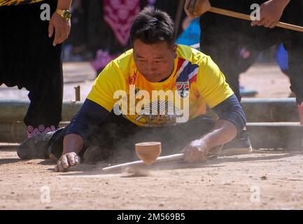 Un uomo della tribù di Hmong che gioca la concorrenza di filatura superiore (gioco tradizionale di tujlub che coinvolge le cime di legno di filatura urled con la corda ed i bastoni. Mentre una parte superiore sta ancora girando, un'altra persona prova a colpirla. Se non lo colpiscono, sono fuori. Se lo colpiscono, il vincitore è quello la cui cima continua a girare più a lungo.) Durante le celebrazioni del Capodanno di Hmong. In dicembre o gennaio, gli Hmong celebrano il loro nuovo anno, chiamato Noj PEB Cug (pronunciato né PE Chao). Una grande celebrazione pubblica si svolge in un luogo all'aperto, ci sono molte attività durante questo evento, come top-s Foto Stock