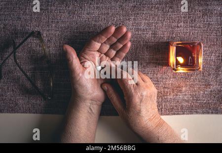 Pillole nelle mani di una vecchia donna, vista dall'alto. Foto Stock