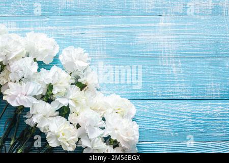Sfondo di legno blu con fiori bianchi, giacitura piatta. Foto Stock