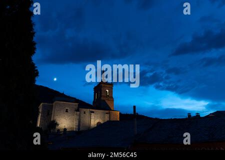 Una luna crescente cerante sorge su Iglesia de San Nicolás de Bari in Molinaseca, León, Spagna. Il paese si trova lungo il Camino Frances, una tipica capra Foto Stock