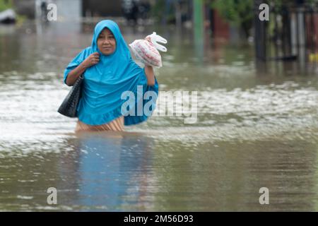 Makassar, Sulawesi del Sud, Indonesia. 26th Dec, 2022. Una donna negozia le acque di alluvione per procurarsi cibo dopo che migliaia di case a Makassar sono state colpite da alluvioni a causa del traboccante livello delle acque del fiume nella Provincia di Sulawesi Sud. Il disastro è stato innescato da forti precipitazioni durante il picco del tempo estremo dal 24 al 25 dicembre 2022. Un certo numero di squadre di soccorso che utilizzano gommoni ha continuato a evacuare e distribuire aiuti alimentari ai residenti intrappolati. (Credit Image: © Moh Niaz Sharief/ZUMA Press Wire) Foto Stock