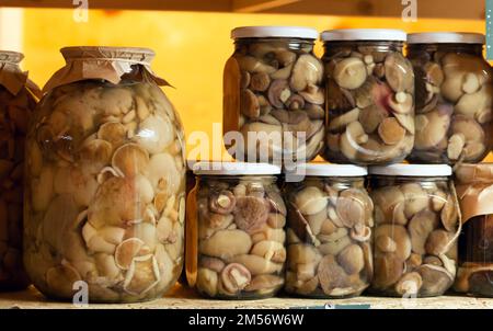 Vasi di vetro con funghi marinati fatti in casa in piedi in una fila su un mercato degli agricoltori checkout Foto Stock