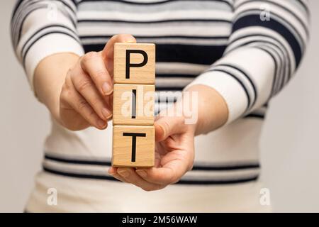 PIT tassation settlement in Polonia, calcolo annuale del reddito e del reddito delle persone fisiche, concetto, Donna in possesso di blocchi di legno con l'iscrizione Foto Stock