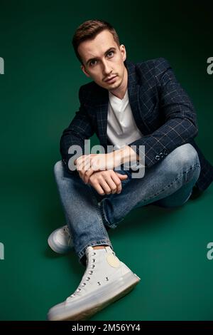 bell'uomo in giacca a plaid seduto sul pavimento Foto Stock