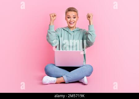 Foto a tutta lunghezza di overjoyed positivo donna indossare abiti alla moda gioire acquistare fresco di qualità netbook macbook isolato su sfondo di colore rosa Foto Stock