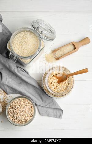 Vasetti con cereali su sfondo di legno chiaro Foto Stock